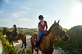 Young woman horseback riding on sunny beach