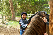 Portrait girl preparing saddle for horseback riding