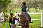 Instructor teaching horseback riding to girl