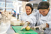Happy young women with Down Syndrome cooking in restaurant