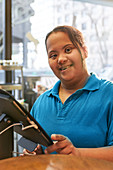 Portrait young woman with Down Syndrome working in cafe