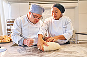 Chef teaching student with Down Syndrome how to form dough