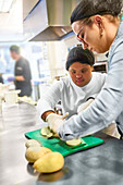 Chef and woman with Down Syndrome cutting potatoes