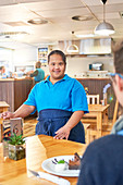 Portrait young female server with Down Syndrome in cafe