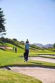 Happy man golfing cheering on sunny golf course