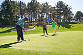 Golfer putting on sunny golf course