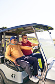 Mature male golfers riding in golf cart