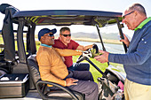 Male golfers talking at sunny golf cart