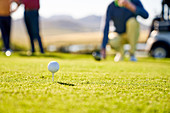 Golf ball on tee in grass on sunny tee box