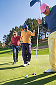 Male golfers at putting green hole
