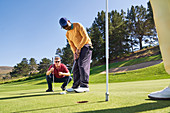 Male golfer putting at hole putting green