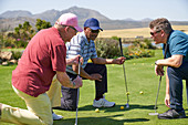 Male golfers kneeling and talking