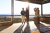 Friends looking at view from sunny safari lodge balcony