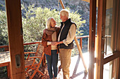 Happy senior couple on sunny safari lodge balcony