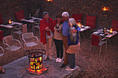 Happy senior friends relaxing at fire pit on hotel patio