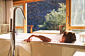 Serene woman taking a bath in sunny hotel room