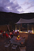 Senior friends relaxing at fire pit on hotel patio