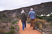 Senior couple holding hands on footpath