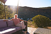 Carefree woman relaxing on sunny safari lodge balcony