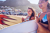 Young women with surfboards on sunny summer beach