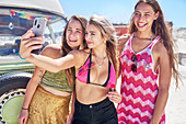 Carefree women friends taking selfie with camera phone
