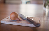 Still life knife and pear on wooden cutting board
