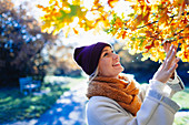 Woman looking up at autumn leaves on tree in park