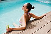 Woman with cocktail relaxing in summer swimming pool