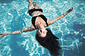 Woman floating in summer swimming pool