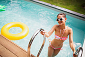 Woman in bikini getting out of summer swimming pool
