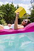 Woman relaxing, reading book on inflatable raft