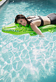 Woman floating on inflatable alligator raft