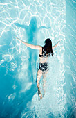 Woman in bikini swimming in summer swimming pool