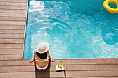 Woman in sun hat relaxing at summer poolside