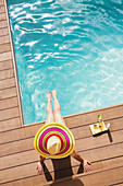 Woman in sun hat relaxing at summer poolside
