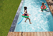 Boy and girl jumping into summer pool