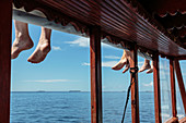 Bare feet dangling over ocean dock, Maldives