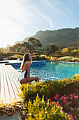 Woman relaxing at idyllic, tranquil swimming pool