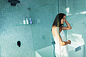 Woman wrapped in towel in modern shower