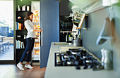 Woman standing at open refrigerator in kitchen
