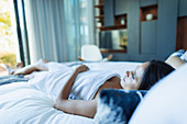 Serene woman wrapped in a towel, relaxing on bed