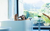 Serene woman relaxing in soaking tub in modern bathroom