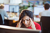 Stressed businesswoman with head in hands in office