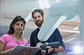 Engineers programming robotic arm in office