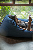 Woman relaxing with digital tablet in beanbag chair