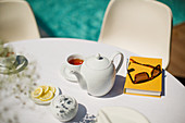 Tea service and book on poolside table