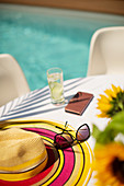 Sun hat and sunglasses on summer poolside patio table