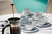 French press and coffee cups on patio table