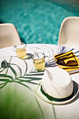 Tea and sun hat on summer poolside patio table
