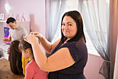 Portrait happy mother fixing daughter hair